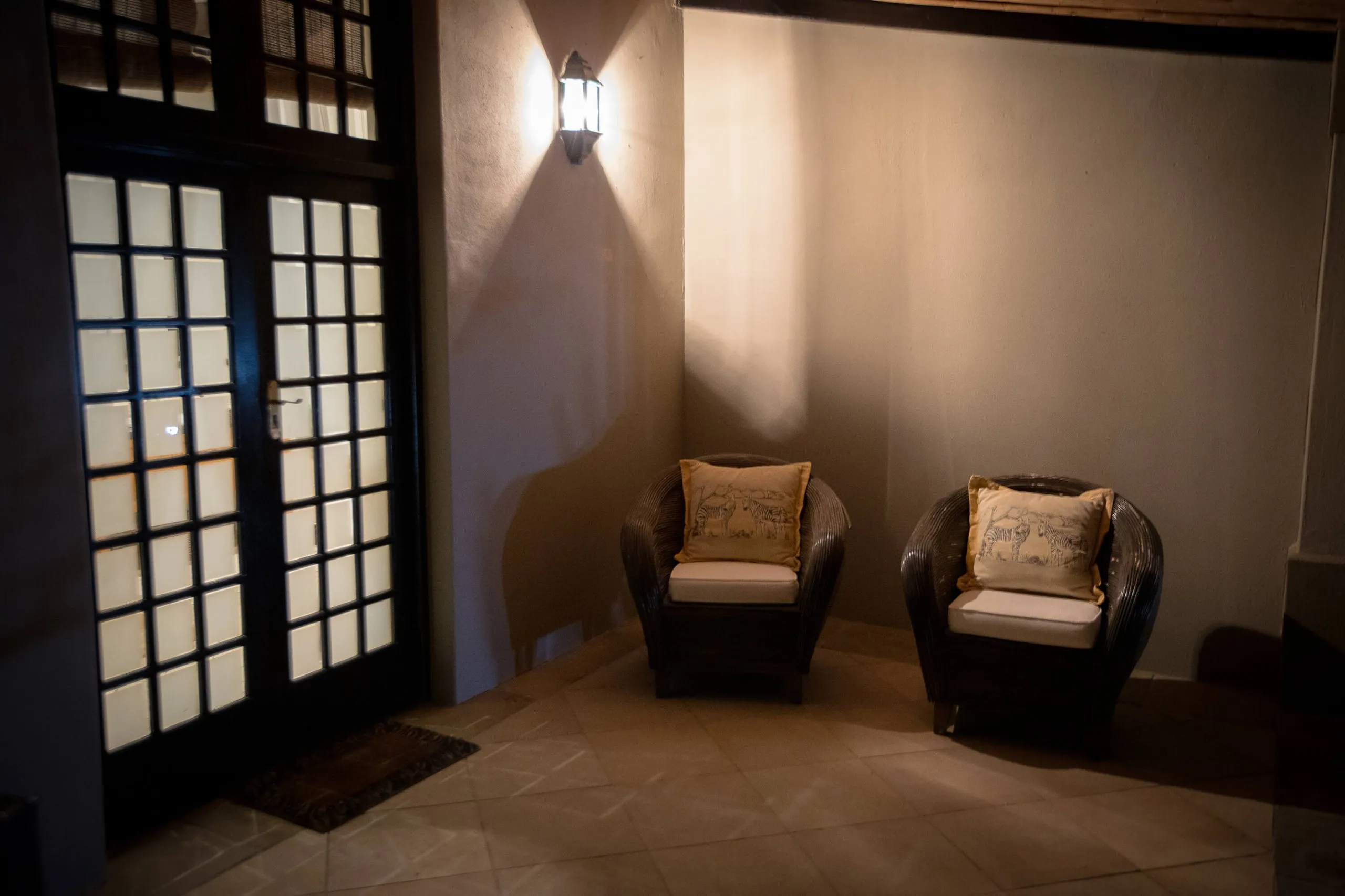 Two armchairs in a dimly lit corner near a door with glass panels