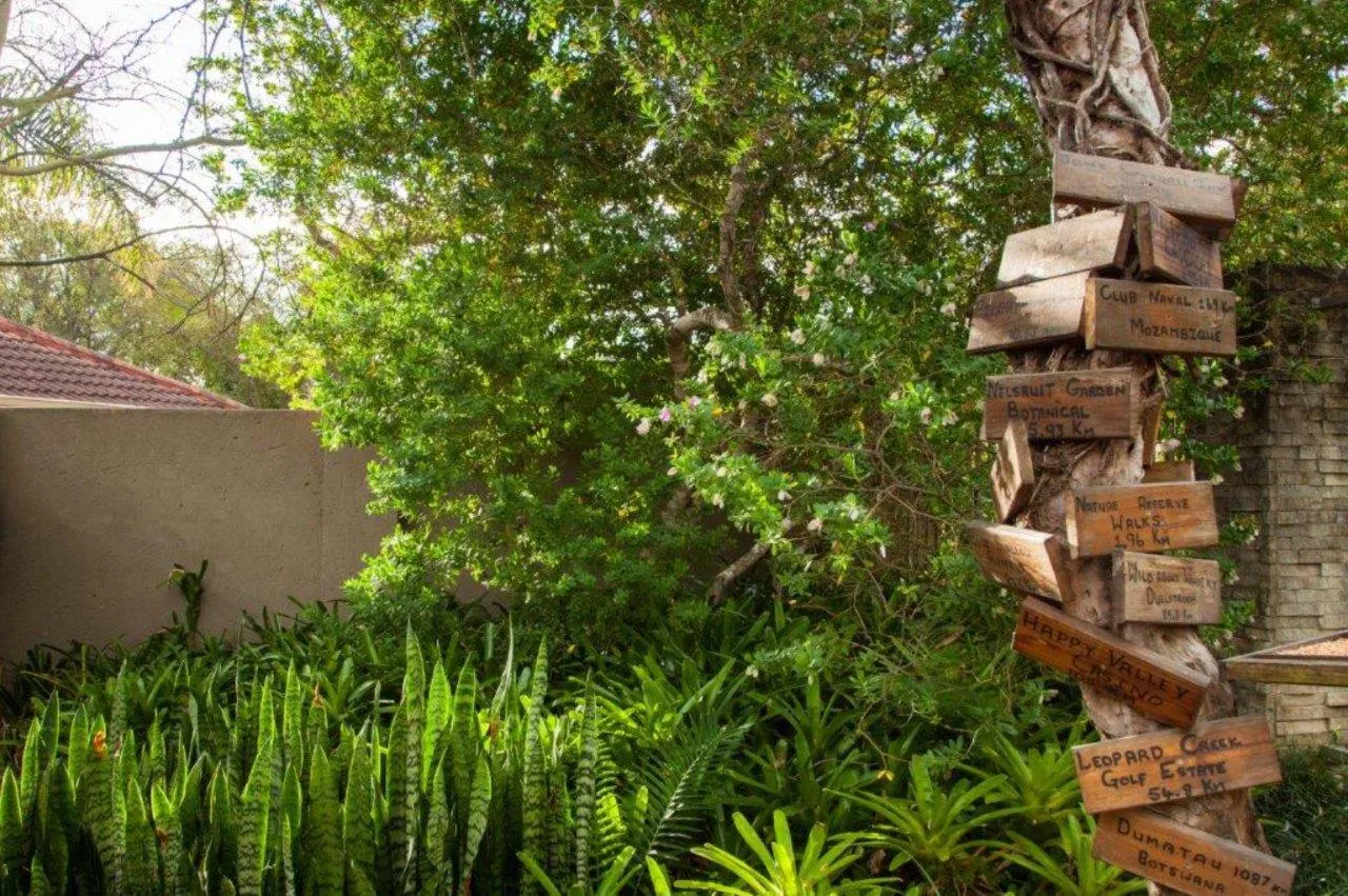 Wooden signpost with multiple directional signs in a lush garden setting