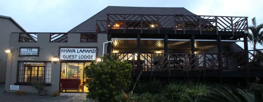 Khaya Lamanzi Guest Lodge building with lit interior and outdoor seating area