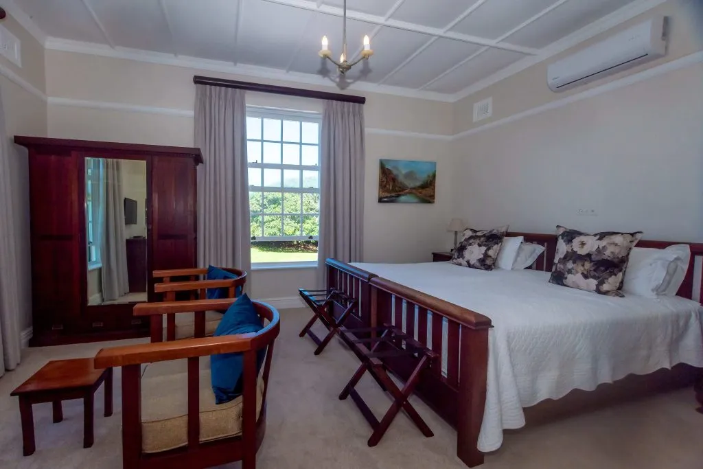 Bedroom with wooden furniture large bed chairs and a window view