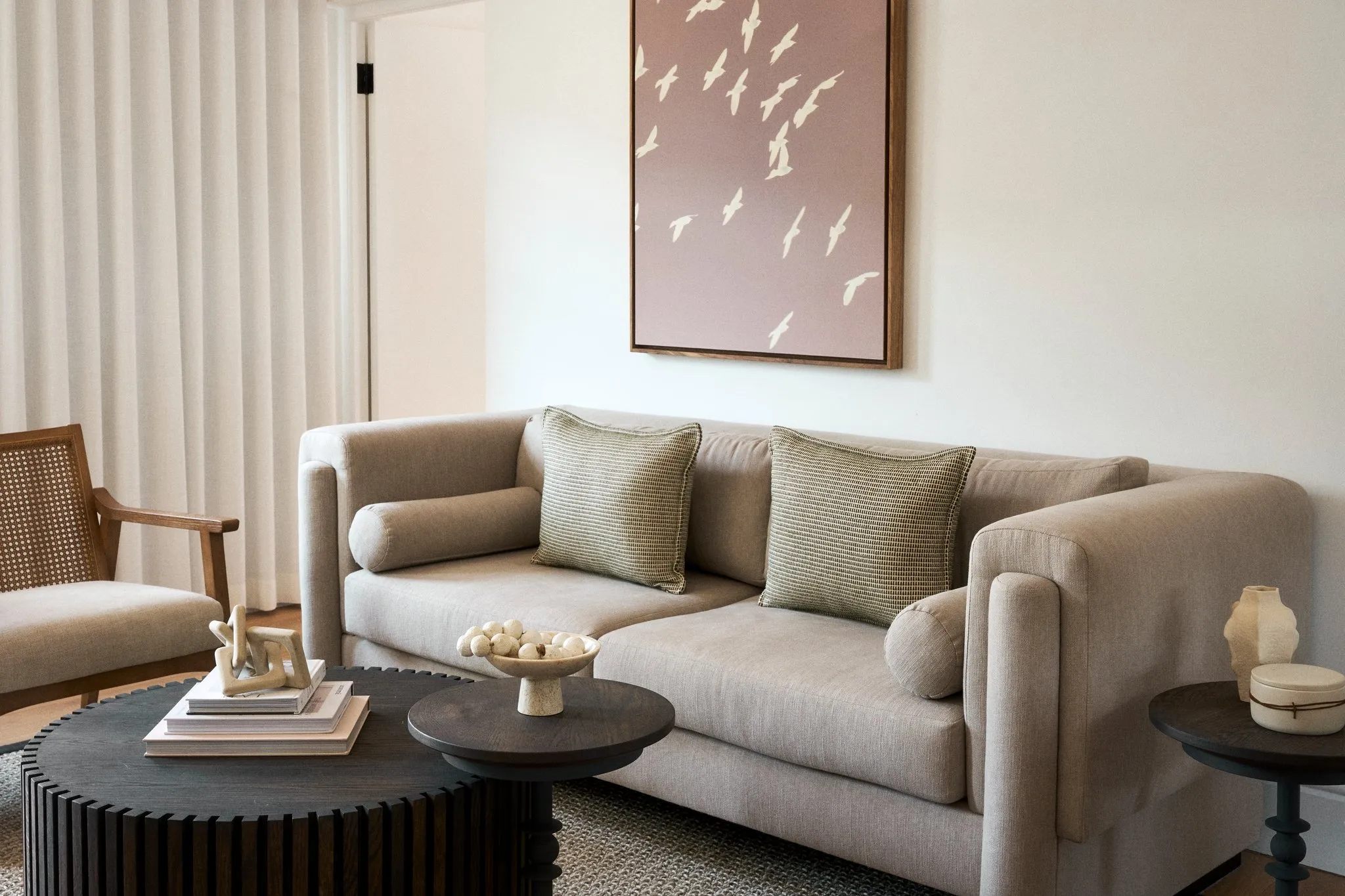 Beige sofa with green pillows wooden coffee table and abstract wall art