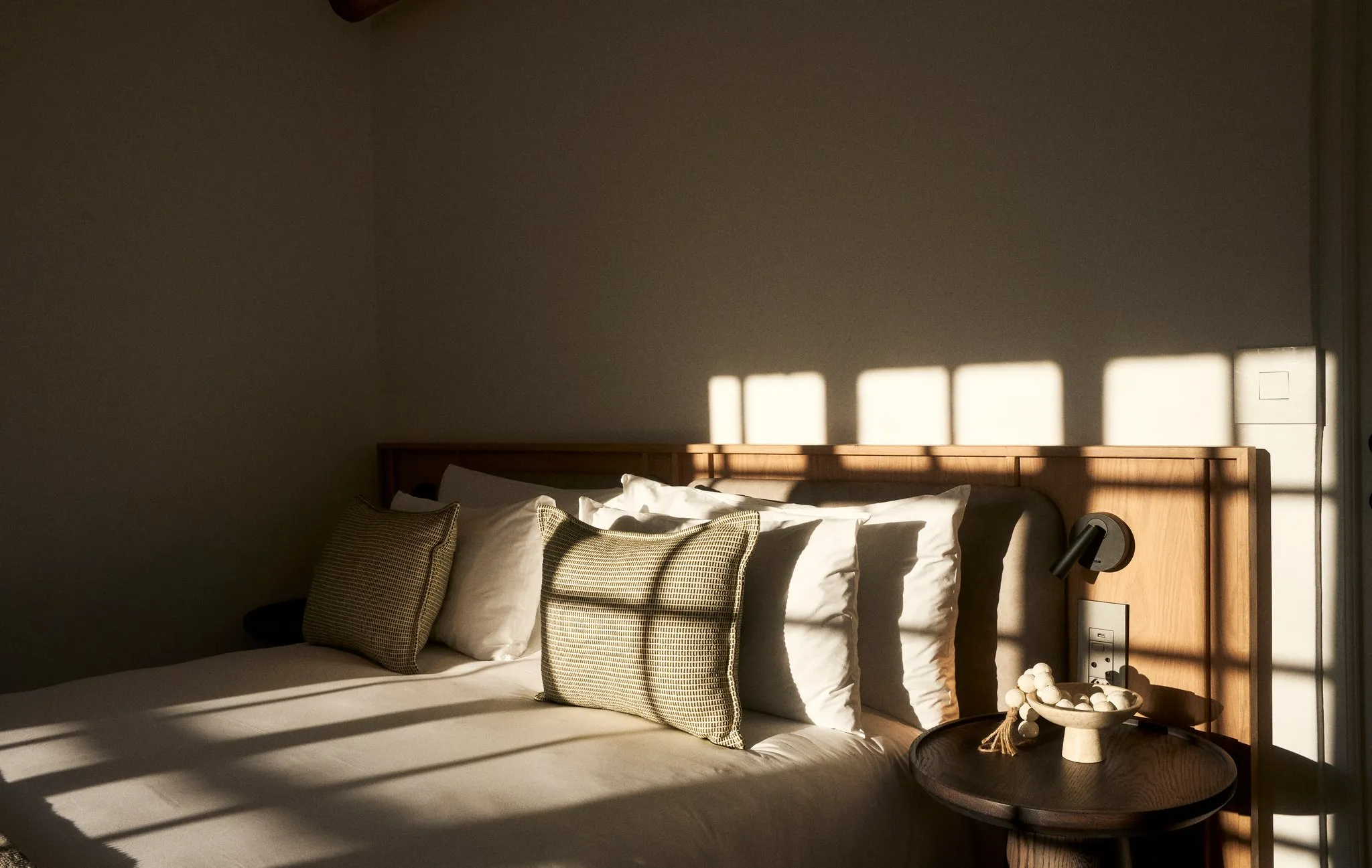 Sunlight streaming onto a bed with pillows in a cozy bedroom