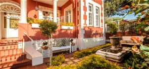 Red and white house with garden fountain and potted plants
