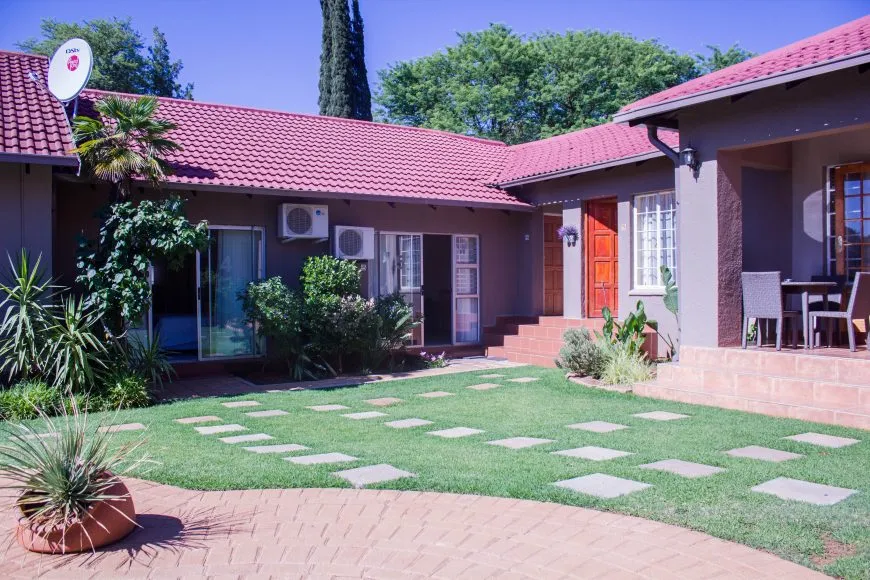 Modern house with red roof green lawn and patio area in sunny weather