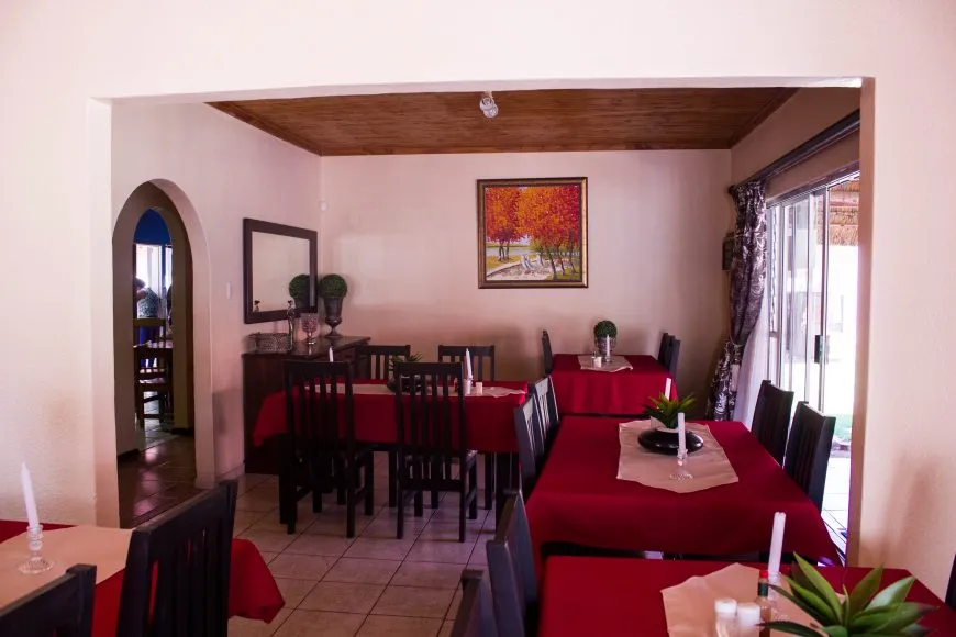 Dining area with red tablecloths wooden chairs and a painting on the wall