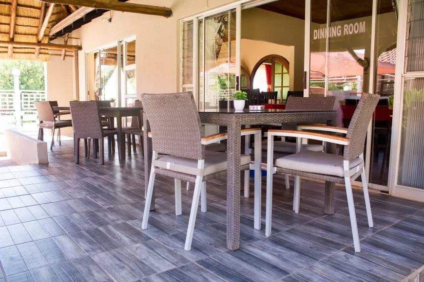 Outdoor seating area with tables and chairs next to a dining room