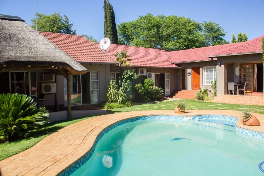 House with redtiled roof and swimming pool in a garden setting