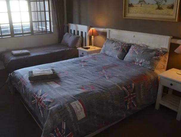 Bedroom with two beds one with Union Jack bedding beside tables and window