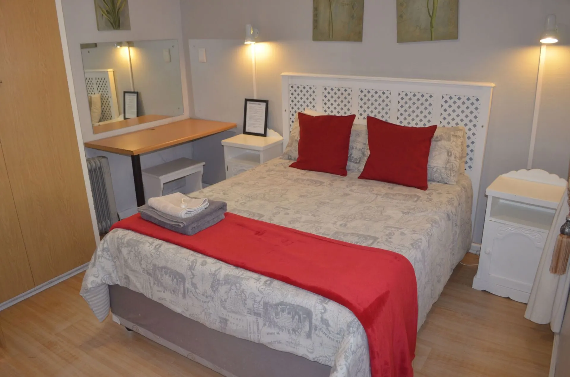 Cozy bedroom with a double bed red pillows and wooden flooring