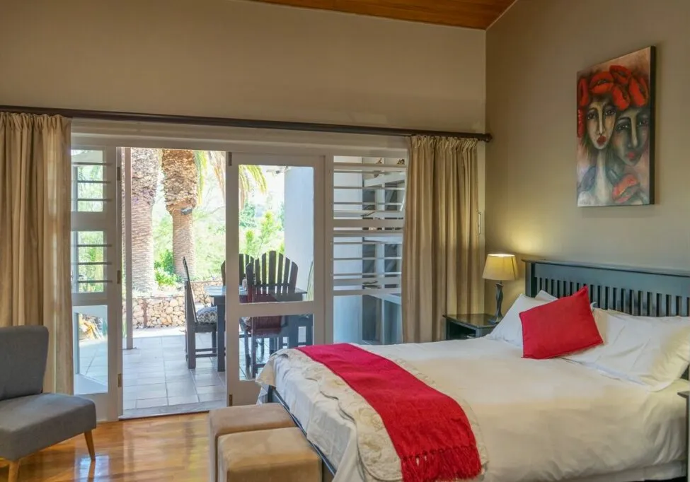 Bedroom with open patio view red blanket and colorful wall art