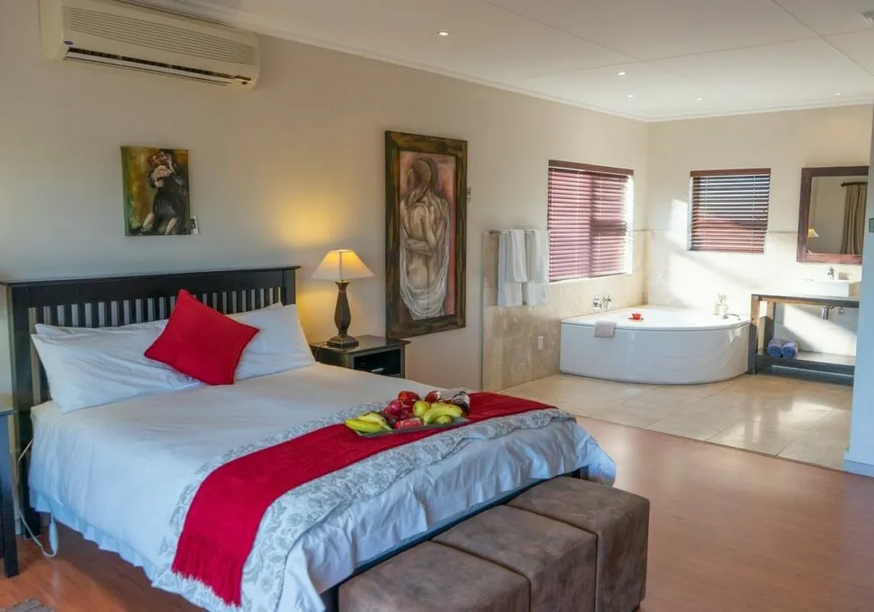 Bedroom with large bed red accents and adjacent bathroom with bathtub