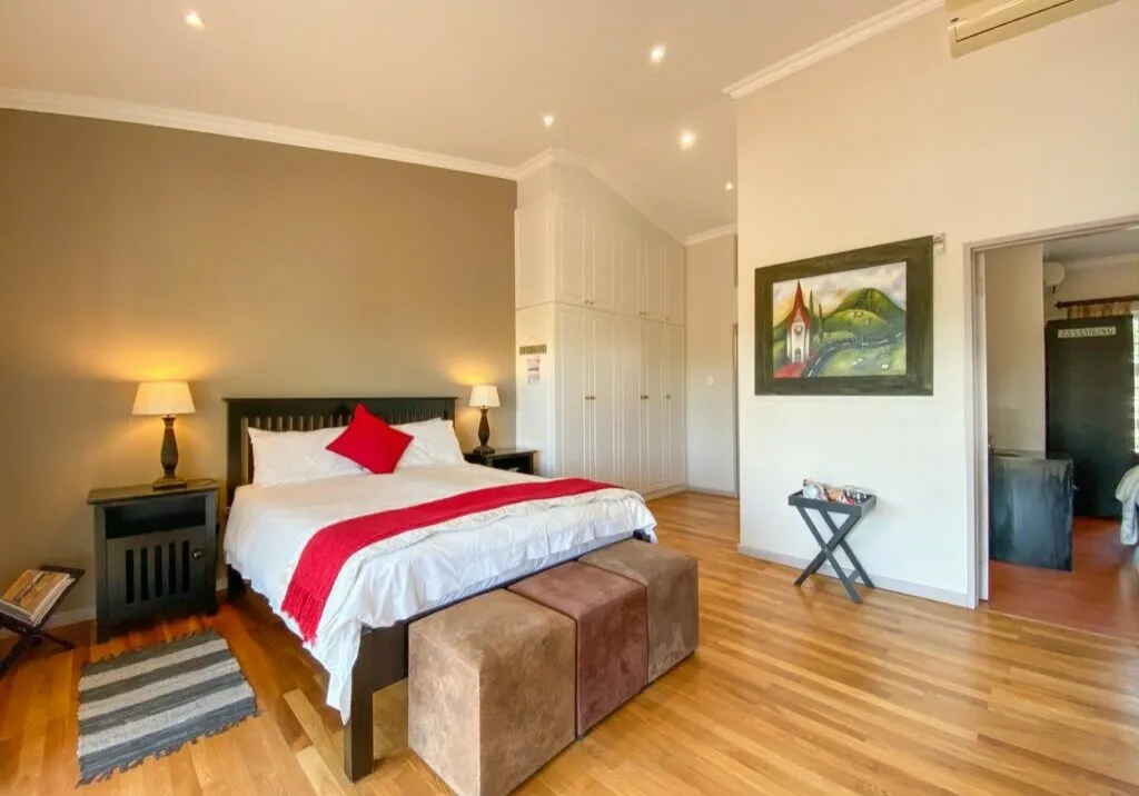 Modern bedroom with large bed wooden floor and artwork on the wall
