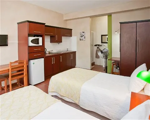 Two single beds in a small room with a kitchenette and wardrobe
