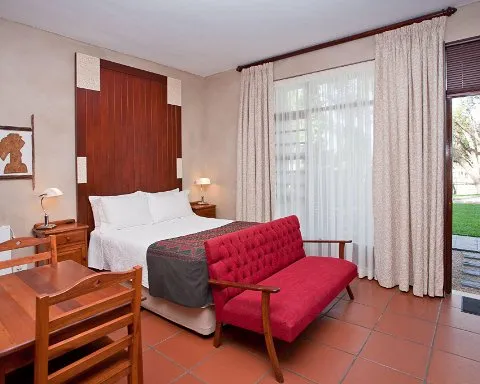 Bedroom with a bed red sofa wooden furniture and large window with curtains