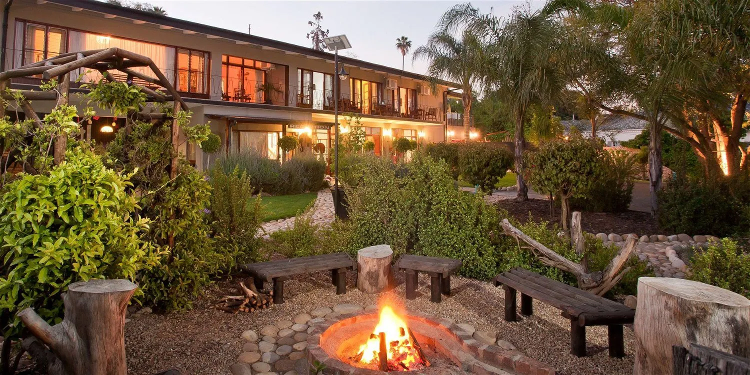 Modern house with outdoor fire pit and lush garden at dusk