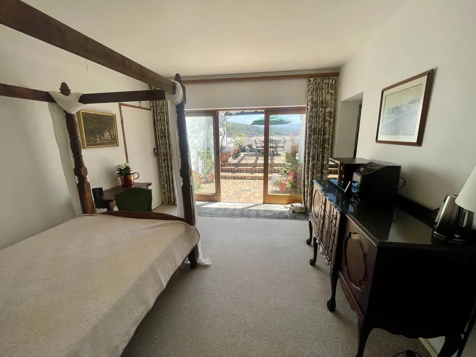 Bedroom with fourposter bed dresser and view of garden through patio doors