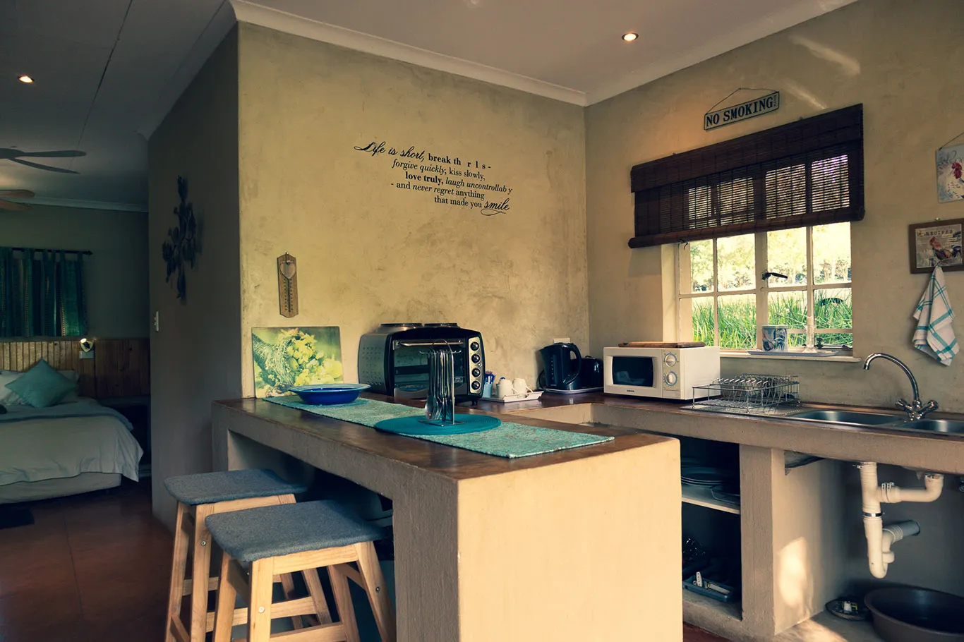 Cozy kitchenette with counter stools appliances and a view of a bedroom