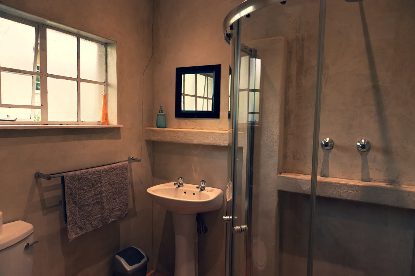 Small bathroom with sink mirror towel and shower area with glass door