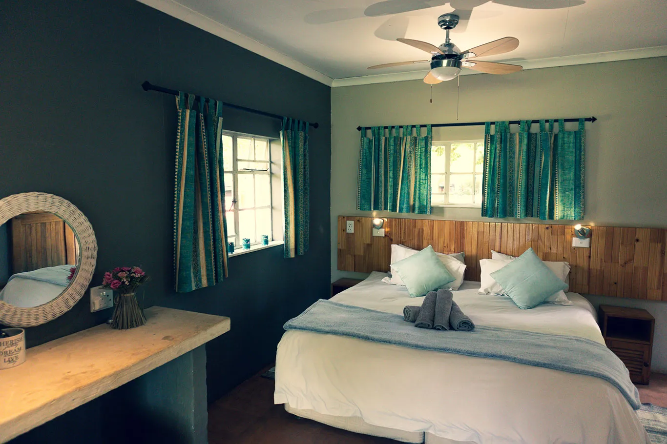 Cozy bedroom with wooden bed green curtains and ceiling fan