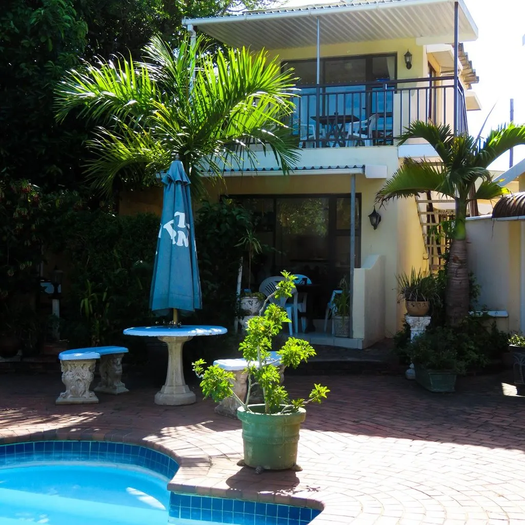 Twostory house with pool palm trees and patio furniture in sunny backyard