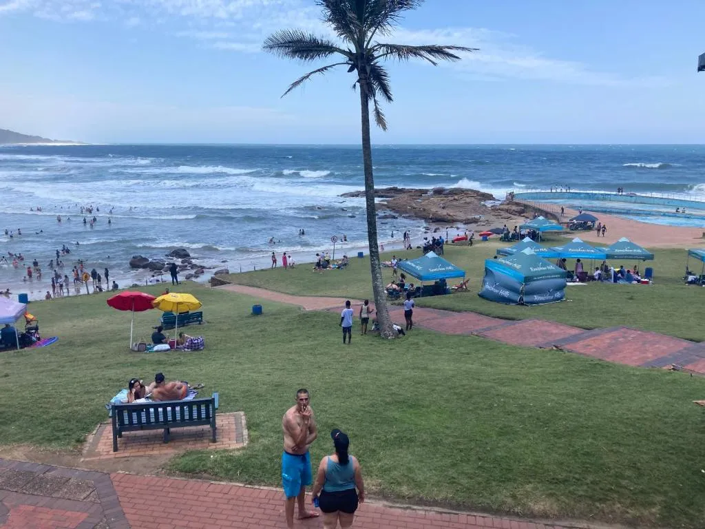 Beach scene with people palm tree tents and ocean waves in the background