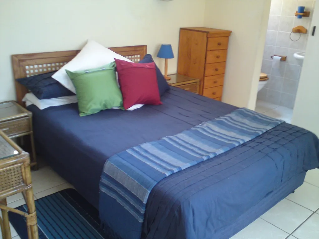 Bedroom with a neatly made bed bedside tables and a bathroom entrance