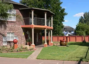Brick house with balcony garden and lawn under a blue sky