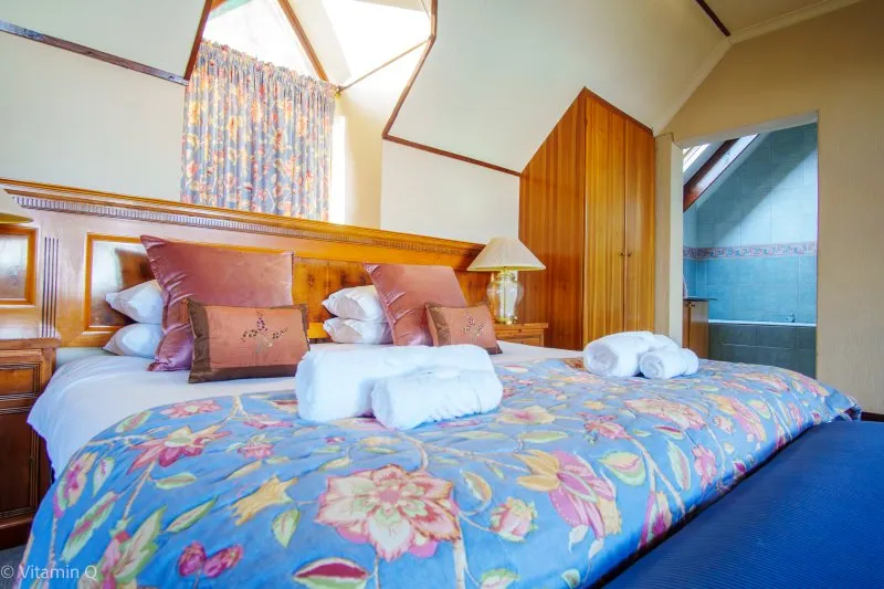 Cozy bedroom with a large bed floral bedding and an ensuite bathroom