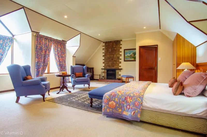 Cozy bedroom with a fireplace floral bedspread and armchairs near large windows