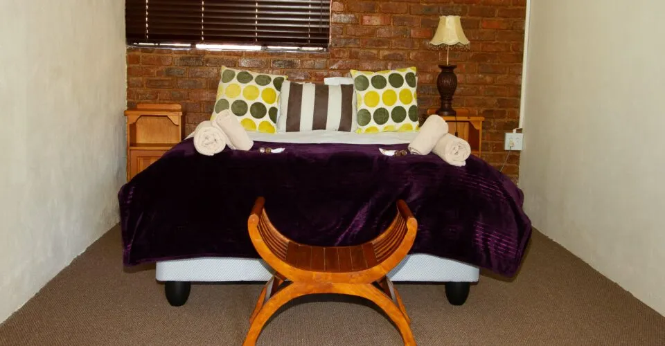 Cozy bedroom with a bed wooden bench and brick wall backdrop