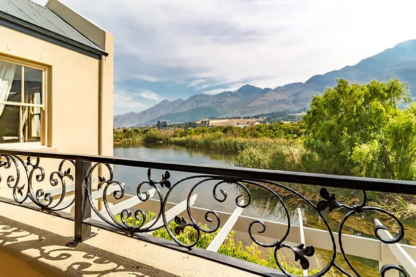 Balcony with wrought iron railing overlooking a river and mountains