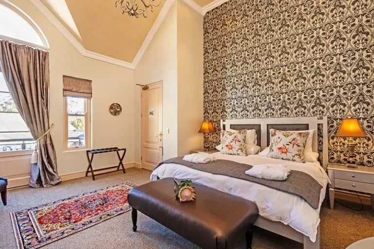 Cozy bedroom with patterned wallpaper large bed and bedside lamps