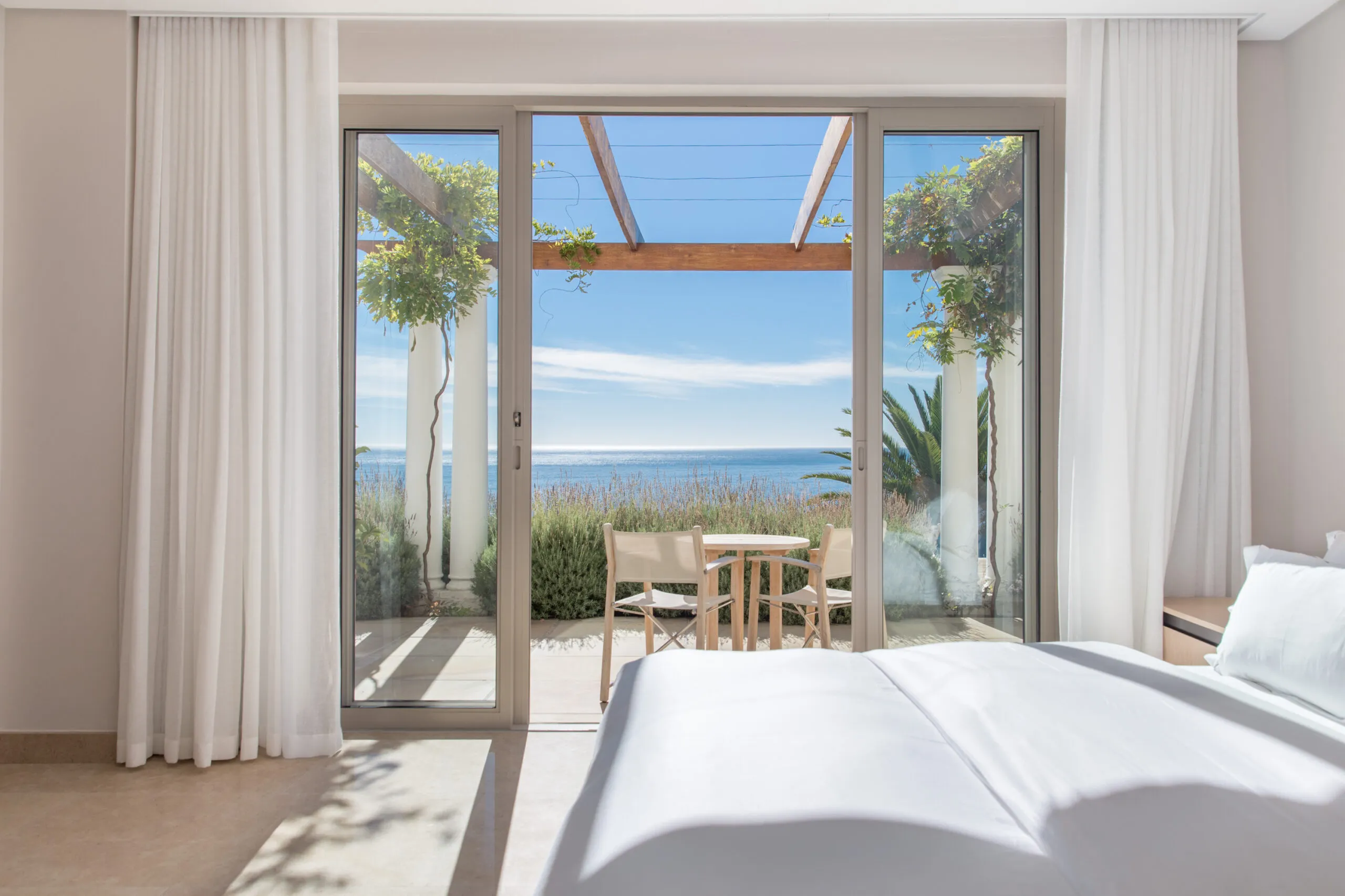 Bedroom with large open doors leading to a patio with ocean view