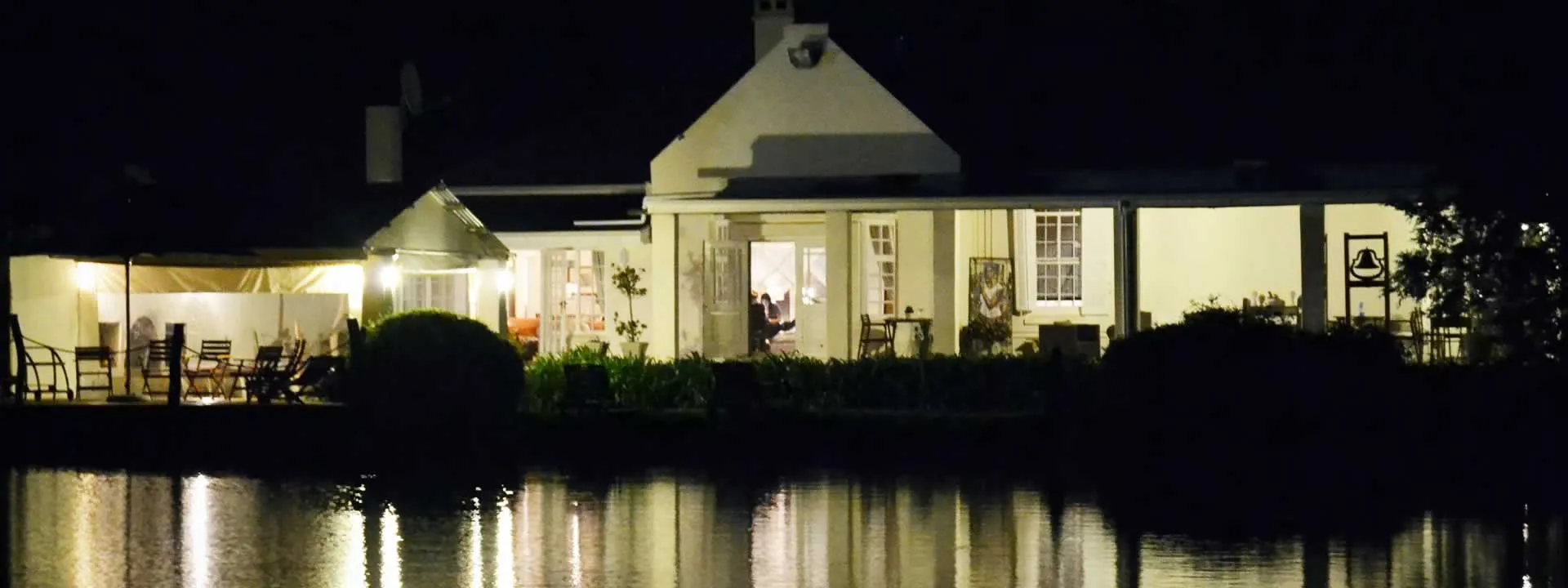 House lit up at night by a lake with reflection on water