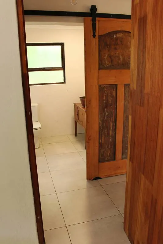 Wooden sliding door open to a small bathroom with a toilet and window