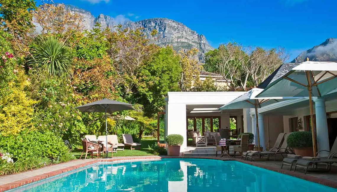 Swimming pool with lounge chairs umbrellas and mountainous backdrop