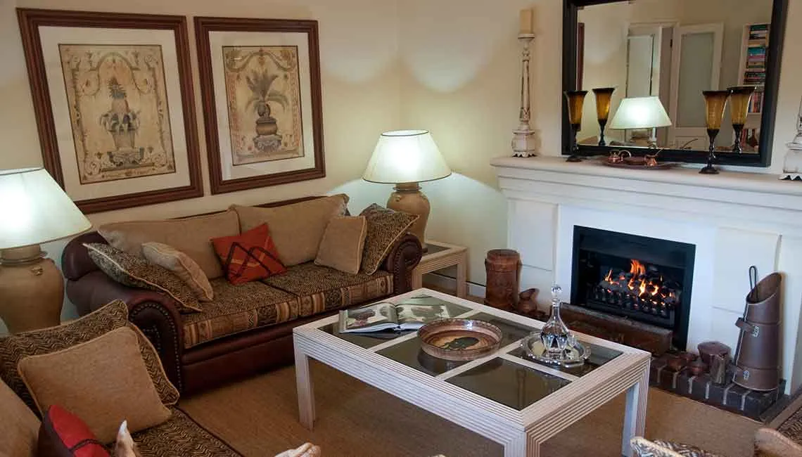 Cozy living room with a lit fireplace sofa coffee table and framed artwork