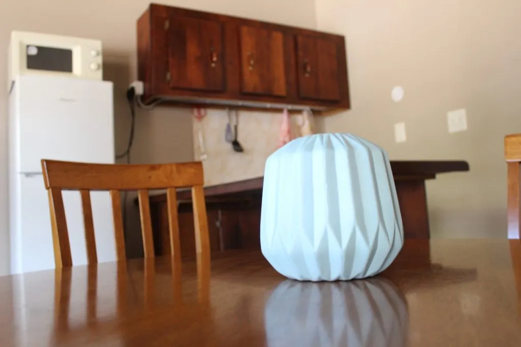 Wooden kitchen with white fridge cabinets and a decorative lamp on a table