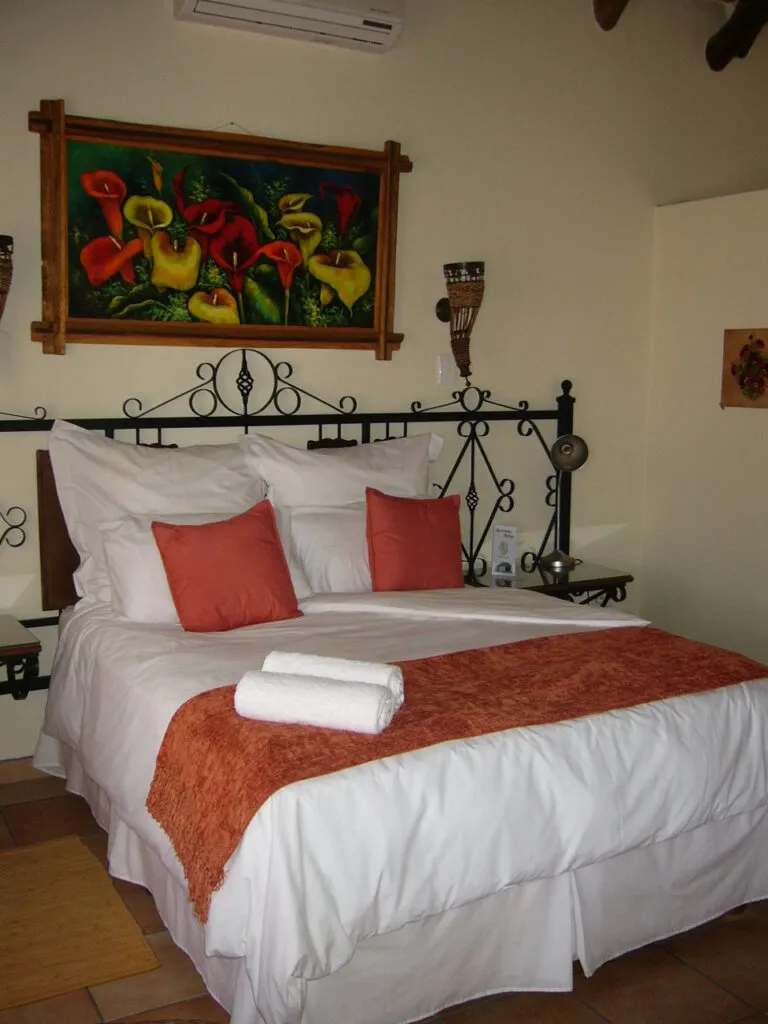 Bedroom with a bed colorful painting and wrought iron headboard