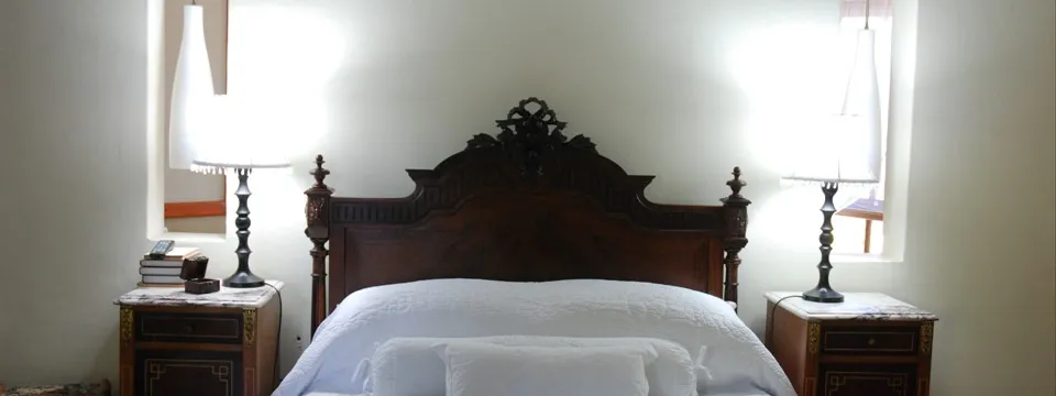 A neatly made bed with wooden headboard and two bedside tables with lamps