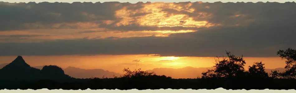 Sunset with mountain silhouette and dark clouds in the background