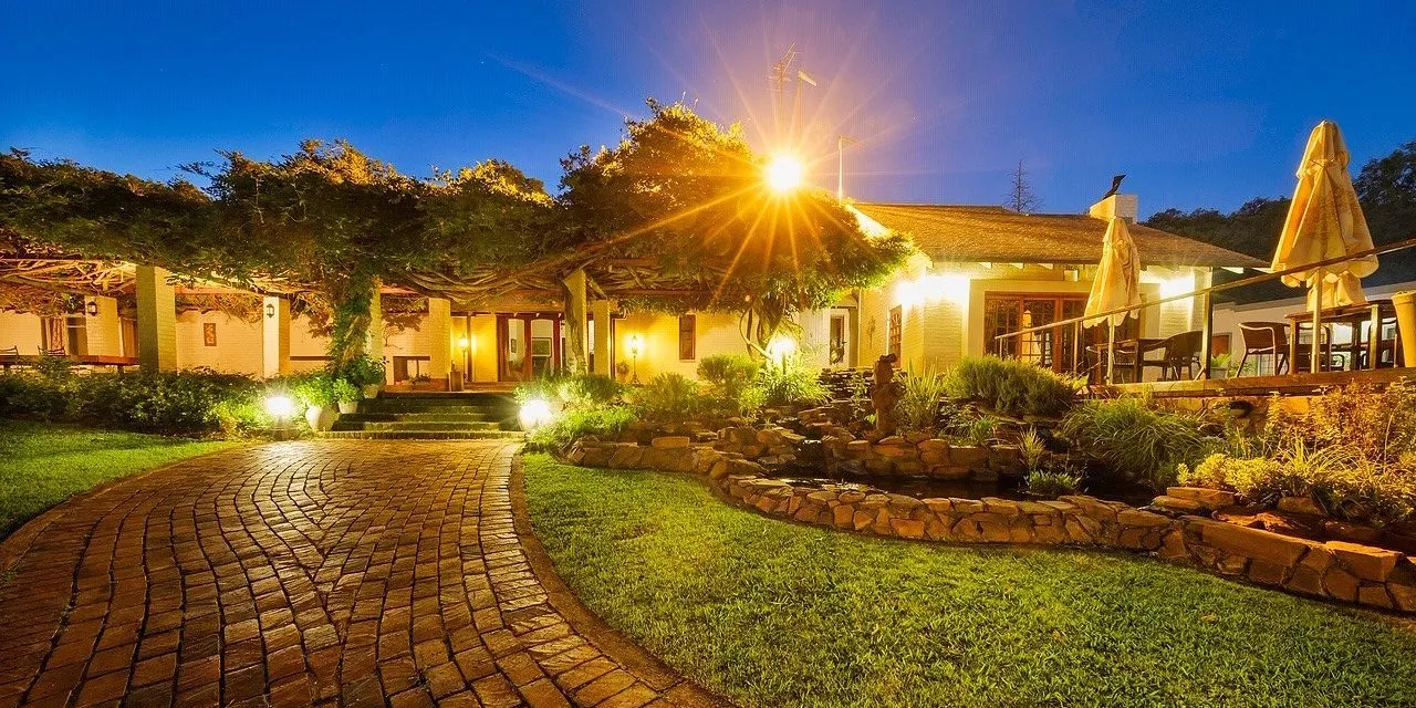 Evening view of a welllit house with a brick pathway and garden