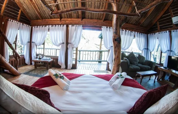 Cozy bedroom with large bed white curtains and wooden interior overlooking a balcony