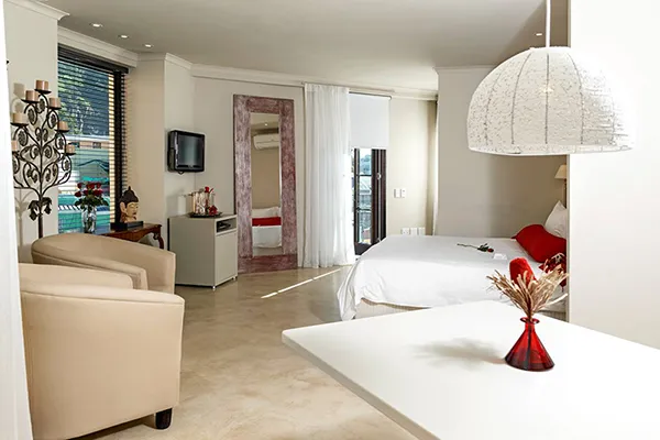 Modern hotel room with bed seating area and a white table with red vase