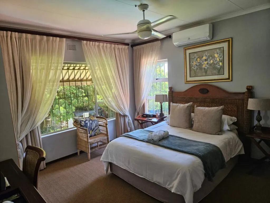 Cozy bedroom with large bed sheer curtains and garden view through windows