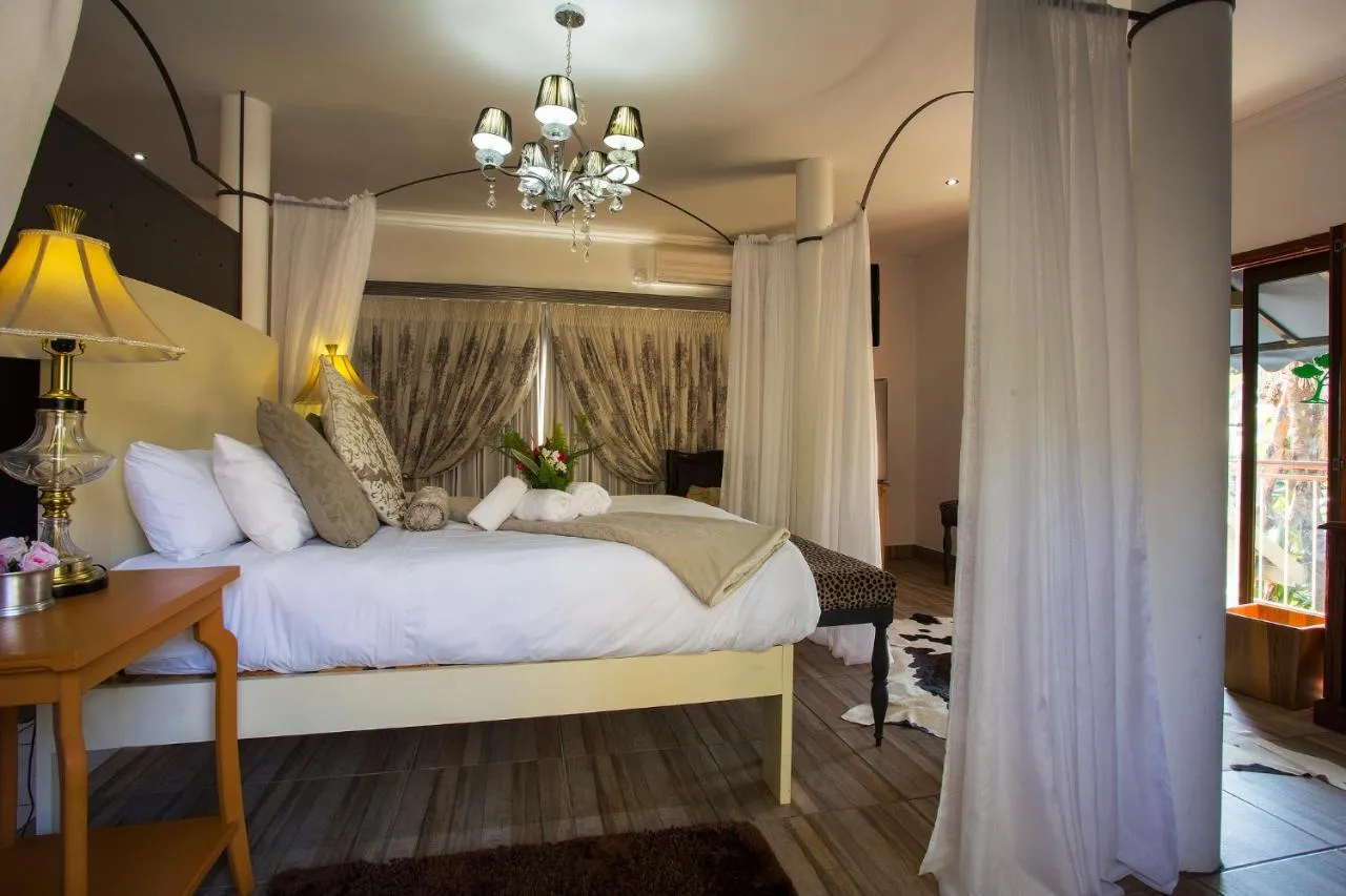 Elegantly decorated bedroom with a large bed chandelier and draped curtains