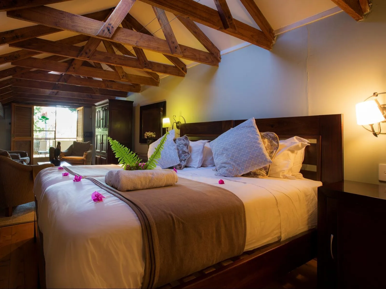 Cozy bedroom with large bed pillows and wooden ceiling lit by bedside lamp