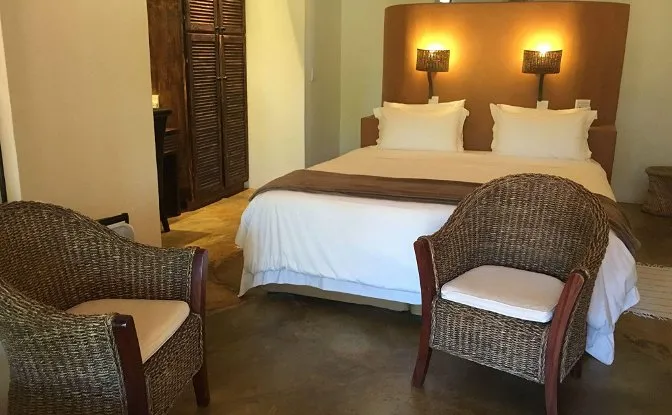 Bedroom with a large bed two wicker chairs and wooden wardrobe