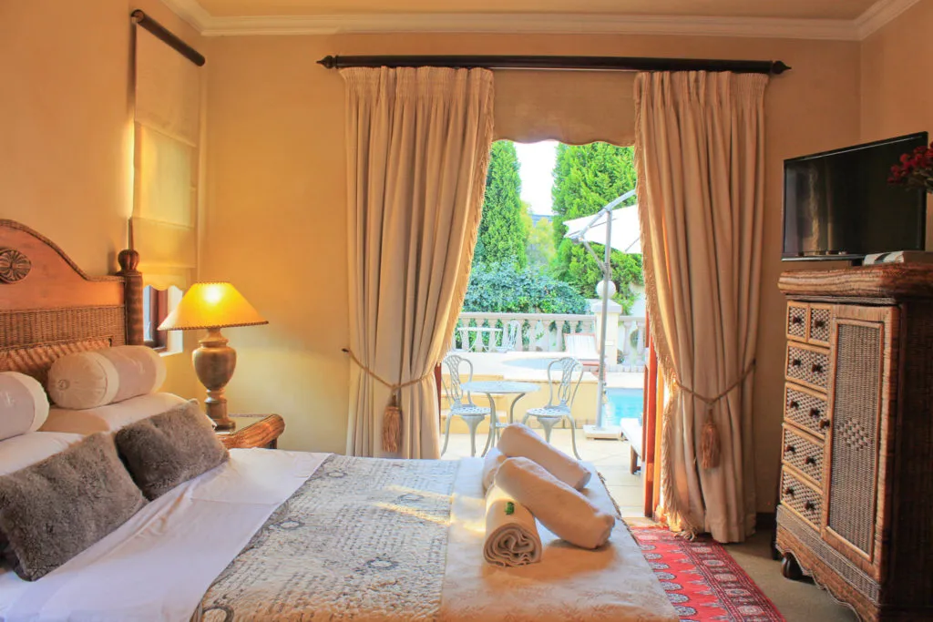 Bedroom with bed TV and open door leading to outdoor patio with pool