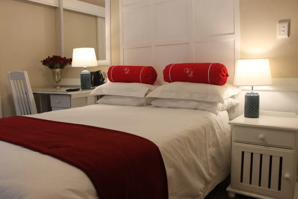White bedroom with a bed featuring red pillows and a red throw